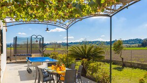 An outdoor patio with a table and chairs, a ping pong table, and a view of the countryside. - Villa Vernissa (Santa Margalida)