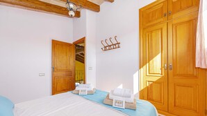 A hotel room with a bed, a wooden wardrobe, a coat rack, and a bathroom visible through an open door. - Villa Vernissa (Santa Margalida)