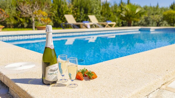 A poolside setting with a bottle of champagne, glasses, and strawberries. - Villa Vernissa (Santa Margalida)