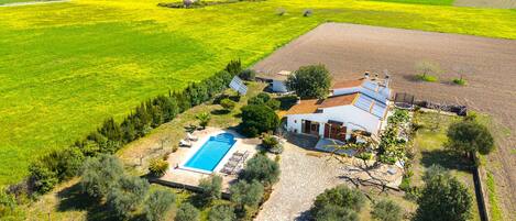 A house with a swimming pool, solar panels, and a stone pathway.