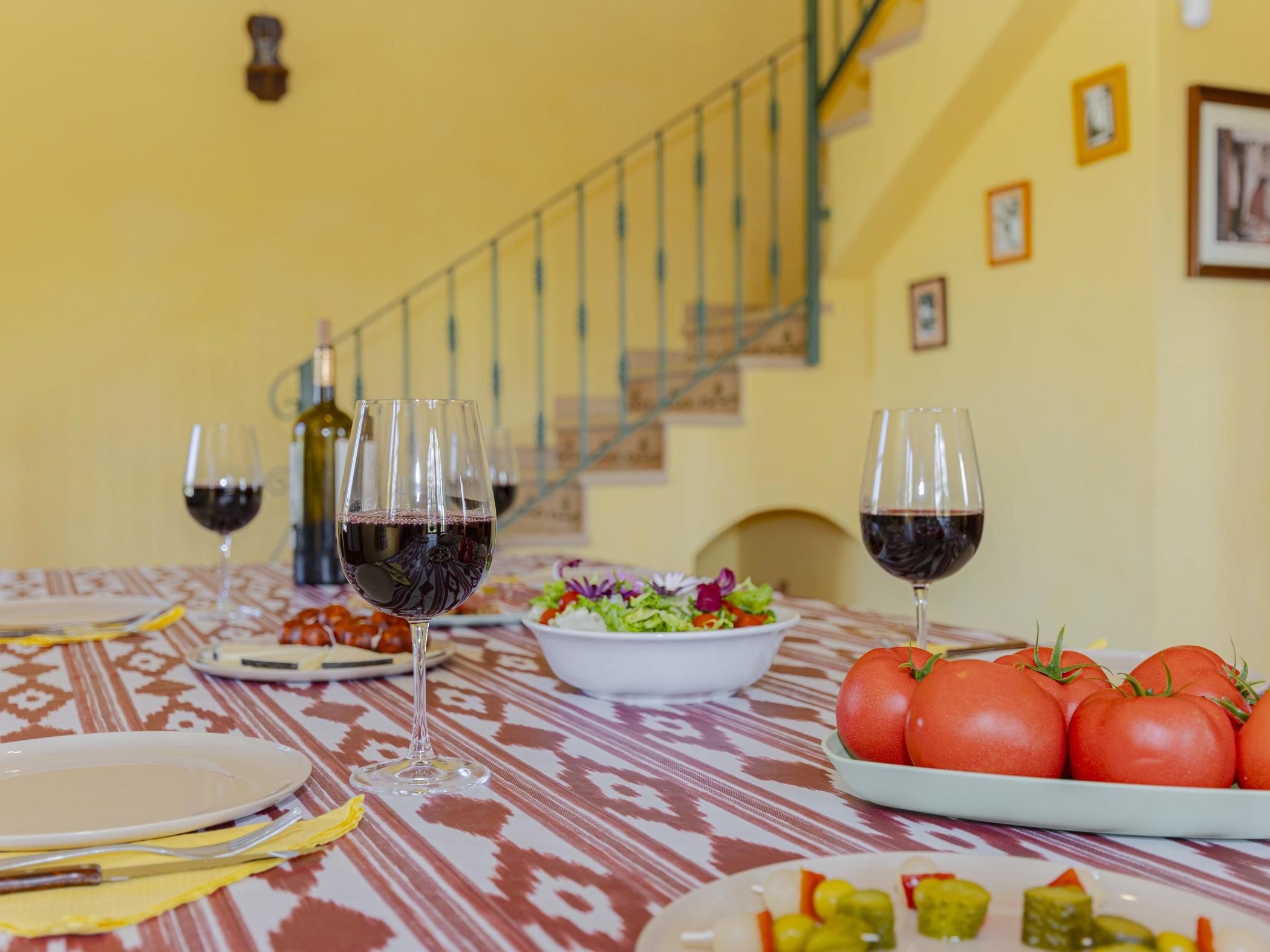 A dining table with plates, glasses, and a bowl of salad.
