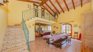 A spacious dining area with a long wooden table, a staircase with decorative tiles, and a balcony with a railing. - Villa Vernissa (Santa Margalida)