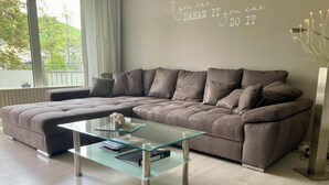 A modern living room with a grey sectional sofa, a glass coffee table, and a motivational wall quote. - KURPARK MAISONNETTE WILLINGEN ***** MOST REVIEWS - 2 BALCONIES - NL OWNER (Willingen (Upland))