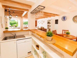 A modern kitchen with a wooden countertop, a built-in dishwasher, and a dining area with a wooden table and chairs. - Villa, only 15 min from Palma, 12 pax, large pool, WIFI FREE, AACC, Sat TV (Marratxinet)