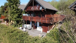 En træhytte med balkon, omgivet af træer.