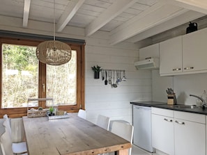 A kitchen with white cabinets, a wooden table, and a hanging light fixture. - Cottage in the heart of the Ardennes  (Dochamps)