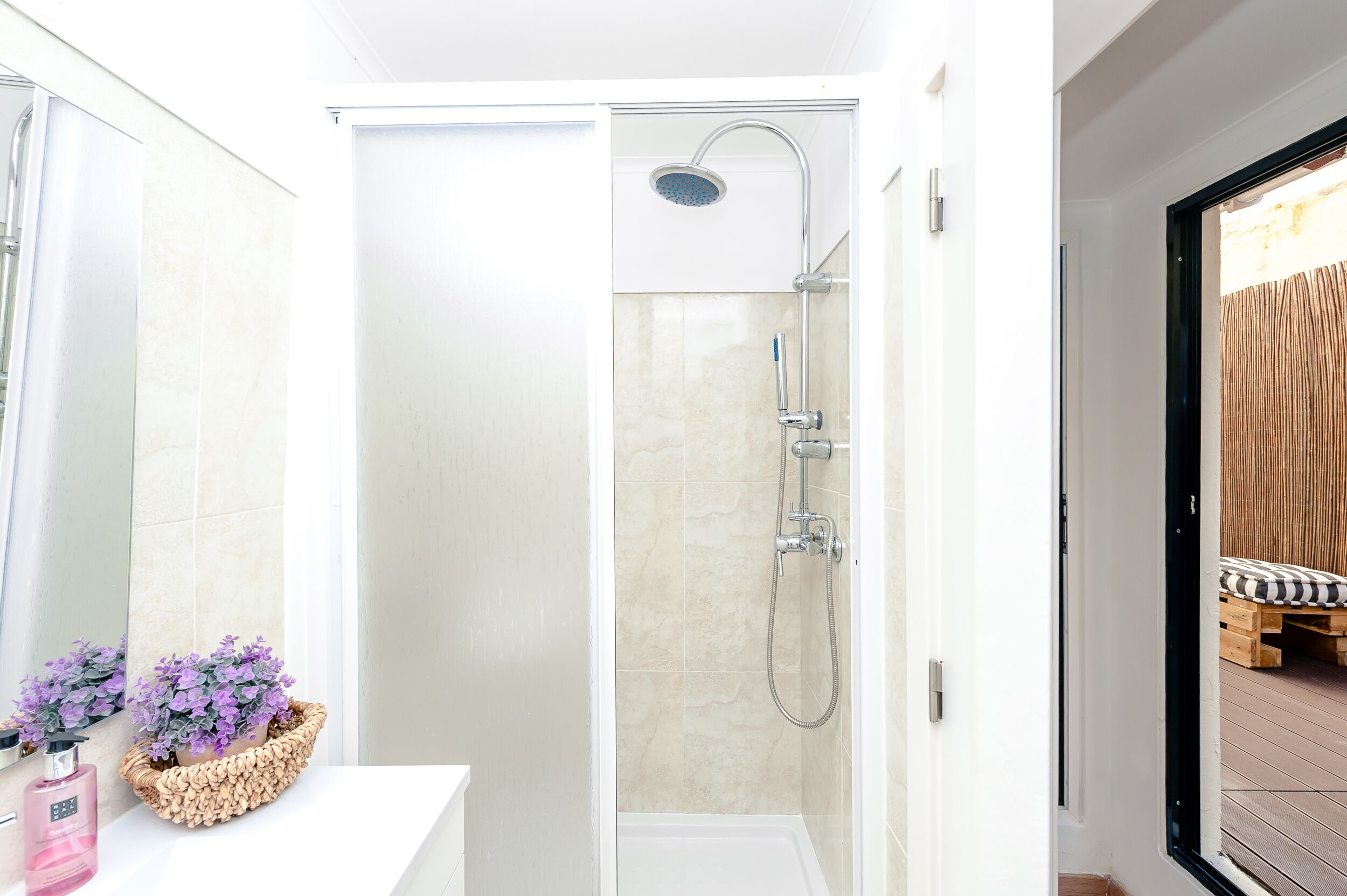Un baño moderno con cabina de ducha de vidrio, un lavabo blanco y una planta decorativa.