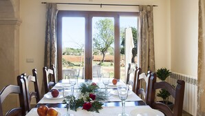 Comedor con mesa dispuesta para seis personas, ventanas grandes con cortinas y vistas al exterior.
