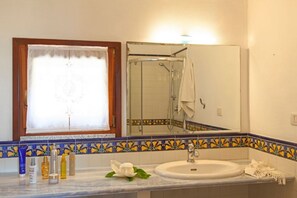 A bathroom with a white sink, a mirror, and a shower. There are toiletries on the counter. - Scrittore - SCRITTORE VILLA (Capoliveri)