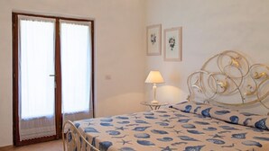 A bedroom with a bed, a lamp, and two framed pictures on the wall. - Scrittore - SCRITTORE VILLA (Capoliveri)