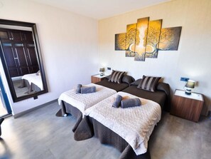 Habitación de hotel con dos camas, un espejo grande, un cuadro en la pared y suelo de madera.