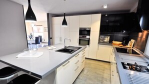 A modern kitchen with white cabinets, a black countertop, and stainless steel appliances. - Luxury Villa with private pool La Herradura (La Herradura)