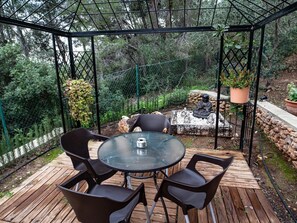 Un patio techado con una mesa redonda de vidrio y cuatro sillas.