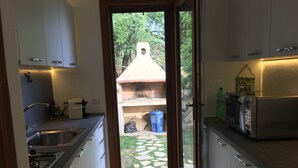 A kitchen with a view of a garden through a glass door. - VILLA DANTE south Sardinia Between countryside and sea (Castiadas)