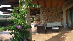 A stone-walled patio with a cushioned seating area and a pergola overhead. - VILLA DANTE south Sardinia Between countryside and sea (Castiadas)