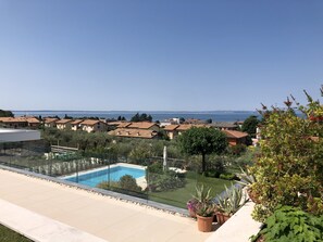 A residential area with a swimming pool, green lawns, and houses with red-tiled roofs.