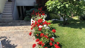 A stone staircase leading to a building entrance, surrounded by a well-maintained garden with red and white flowers. - APARTMENT INSIDE A VILLA, LARGE GARDEN WITH LAKE AND POOL VIEW (Bardolino)