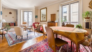 A spacious living room with a dining area, large windows, and a variety of seating options.