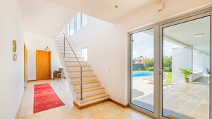 A modern interior with a staircase, a red carpet, and a glass door leading to an outdoor area with a pool. - Villa of charm with private pool overlooking the sea and on the beach (Albufeira)