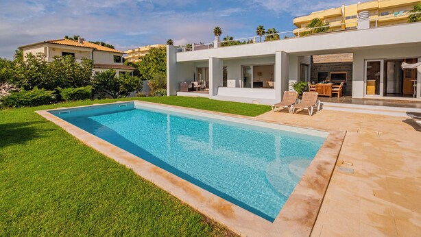 A modern house with a swimming pool, outdoor furniture, and a well-maintained lawn. - Villa of charm with private pool overlooking the sea and on the beach (Albufeira)