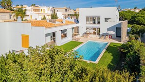 A modern villa with a swimming pool, a covered outdoor seating area, and a view of neighboring houses. - Villa of charm with private pool overlooking the sea and on the beach (Albufeira)