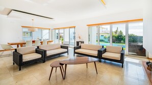 A spacious living area with a large window, a dining table, and comfortable seating. - Villa of charm with private pool overlooking the sea and on the beach (Albufeira)