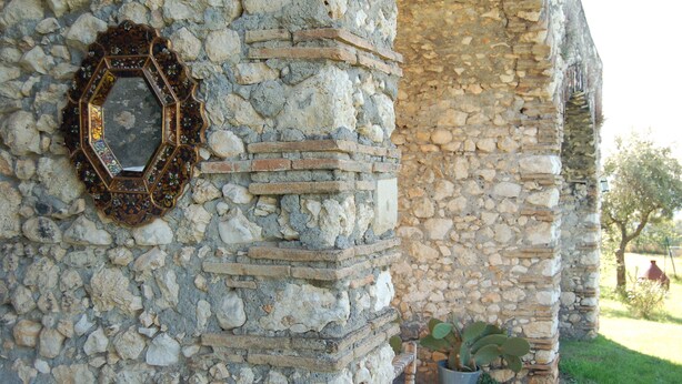 A stone wall with a decorative hexagonal mirror.