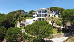 Ein mehrstöckiges Haus mit Pool, umgeben von üppigem Grün und Bäumen.