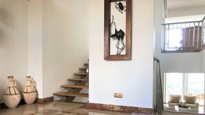 Ein geräumiger Raum mit Fliesenboden, einer Treppe und zwei großen Vasen.