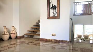 A spacious room with a tiled floor, a staircase, and two large vases.