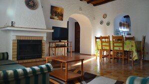 A living room with a fireplace, television, and dining area with chairs and a table. - Villa with Private Swimming Pool / WI-Fi / Pet friendly (8700-176 Olhao)