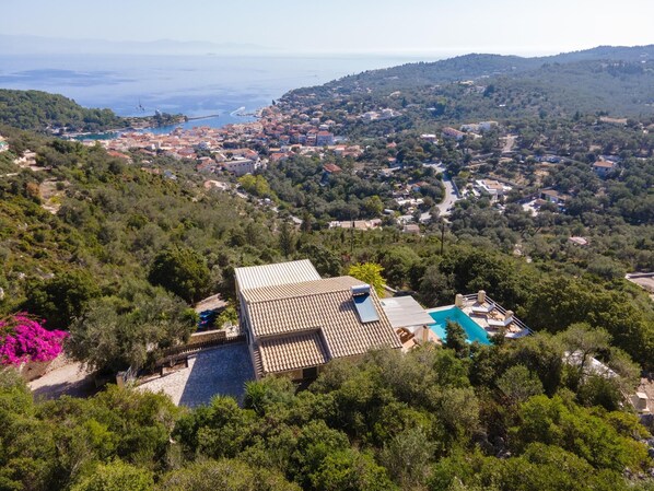 Eine Villa mit Ziegeldach, Swimmingpool und üppiger Bepflanzung.