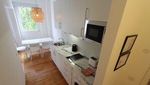 A compact kitchen with a washing machine, a microwave, and a sink. - OPO-APT 112-D Art Deco apartment in city center. AC, wi-fi, cozy and confortable (Portugal)