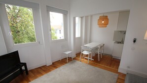 A modern living room with a large window, a dining area with white chairs, a small white table, and a grey sofa. - OPO-APT 112-D Art Deco apartment in city center. AC, wi-fi, cozy and confortable (Portugal)