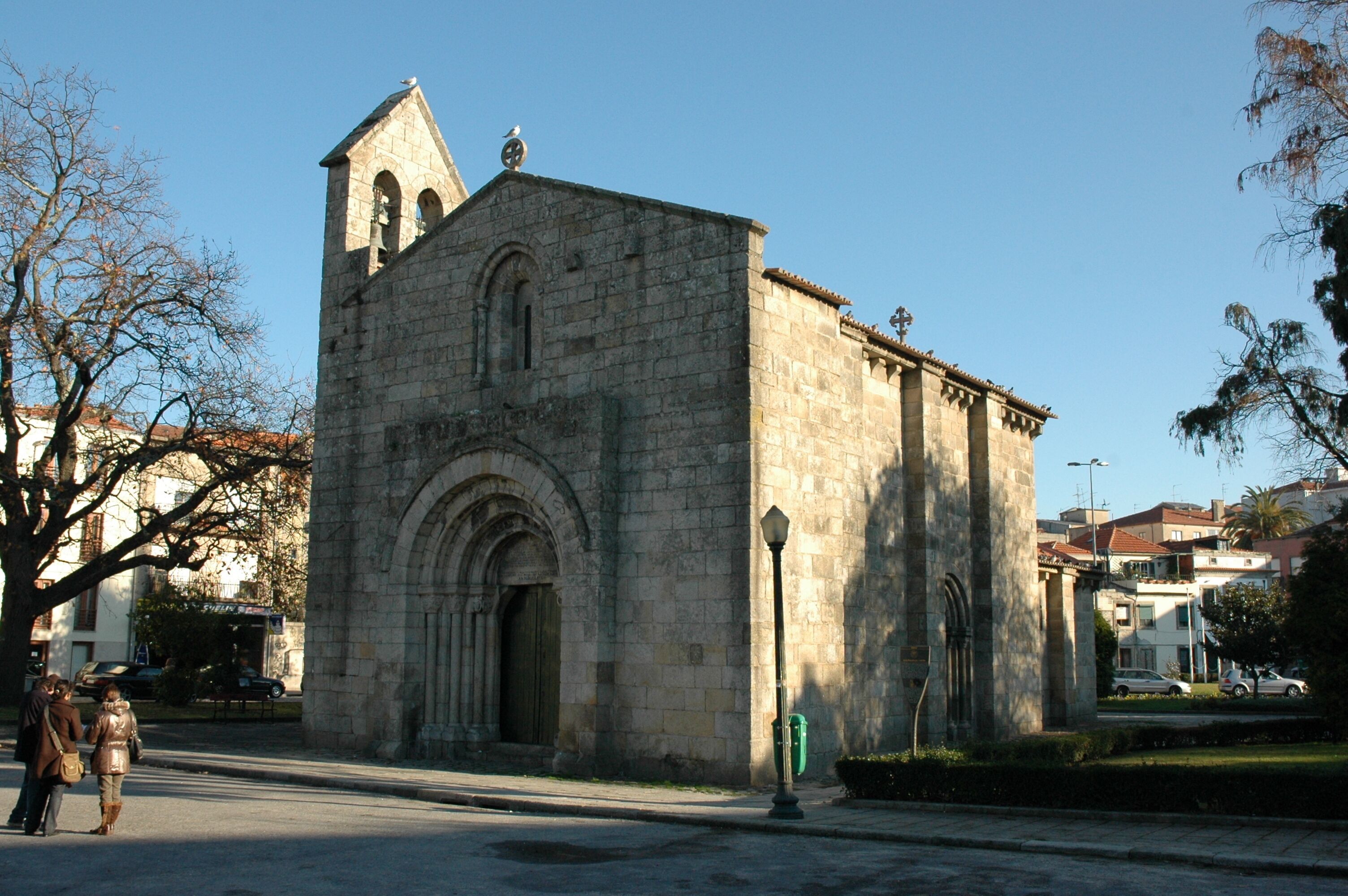 Un edificio in pietra con un campanile, un ingresso ad arco e un lampione di fronte.