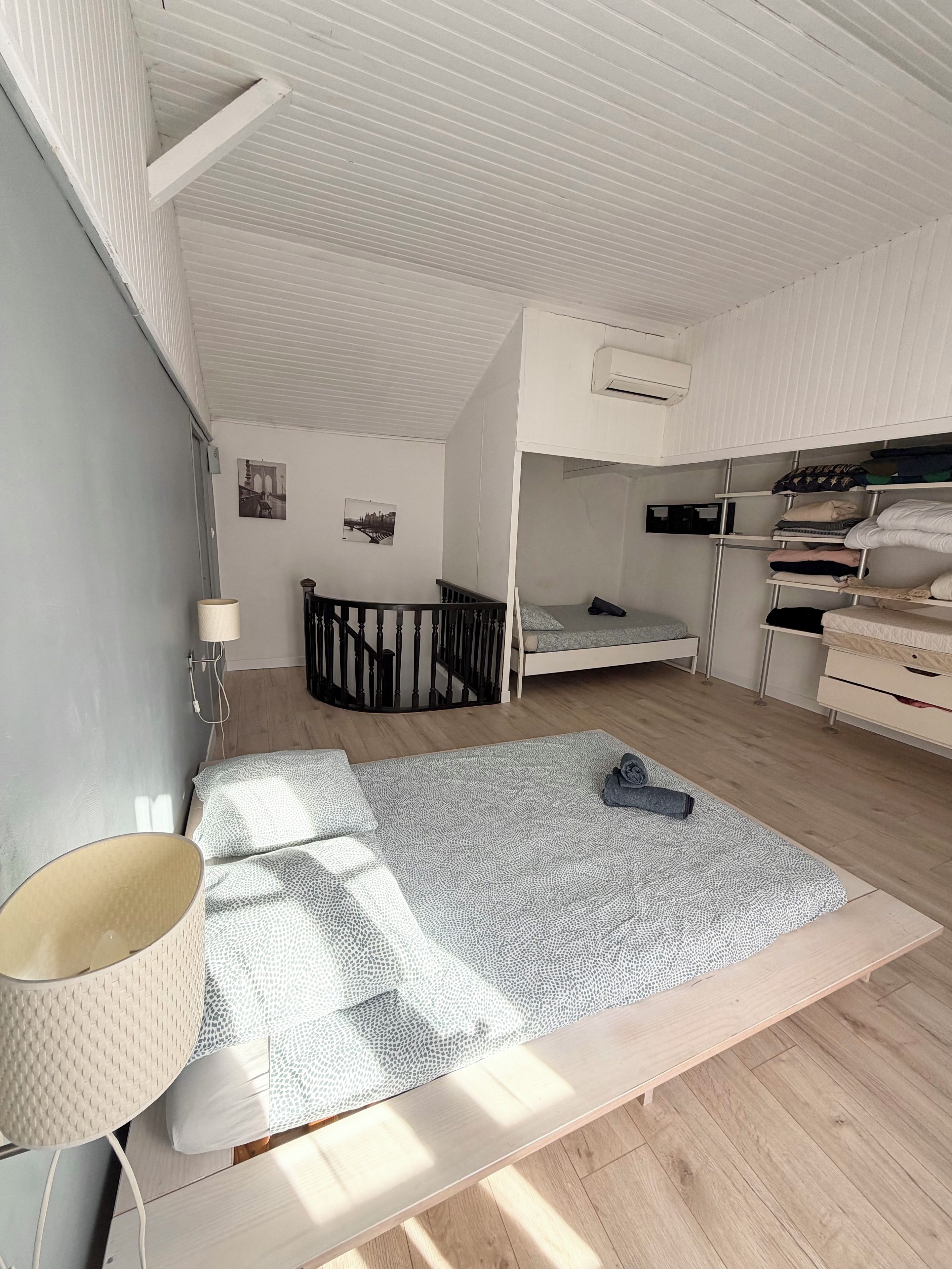 A room with a bunk bed, a desk, a lamp, and a bed with a patterned rug.