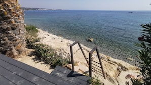 Vista costera con terraza de madera, agua cristalina y una costa distante.
