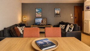 Ein modernes Wohnzimmer mit einer Couch, einem Couchtisch, einem Fernseher und zwei Bildern an der Wand.
