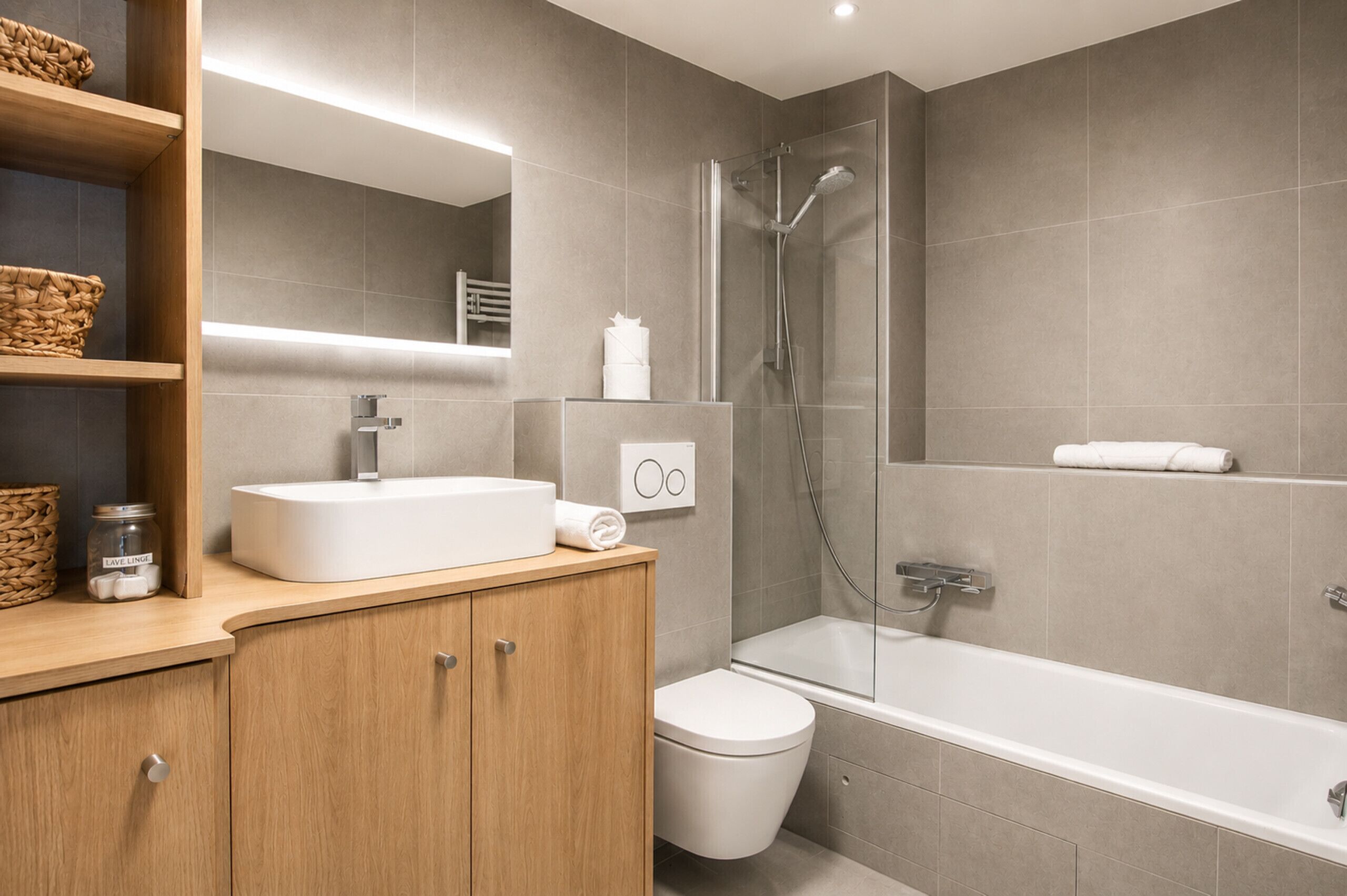 Een moderne badkamer met douche, toilet en wastafel.