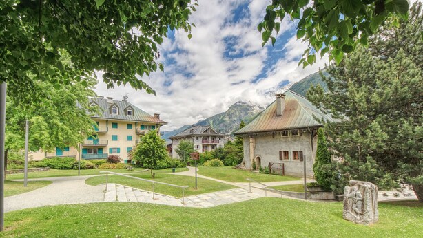 Ein Innenhof mit Gebäuden, einer Steinskulptur und einem Berg im Hintergrund.