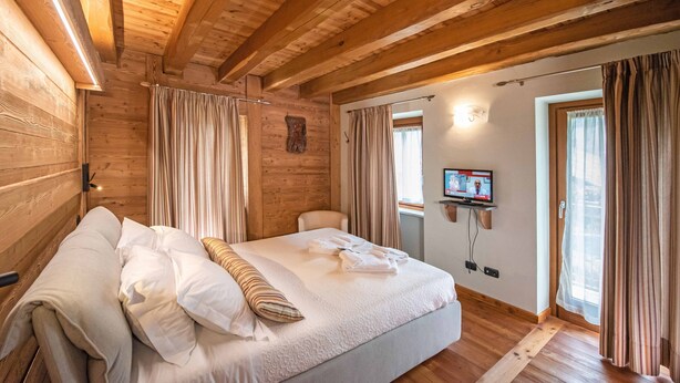 Habitació amb panells de fusta, un llit, cortines, un televisor a la paret i una finestra.