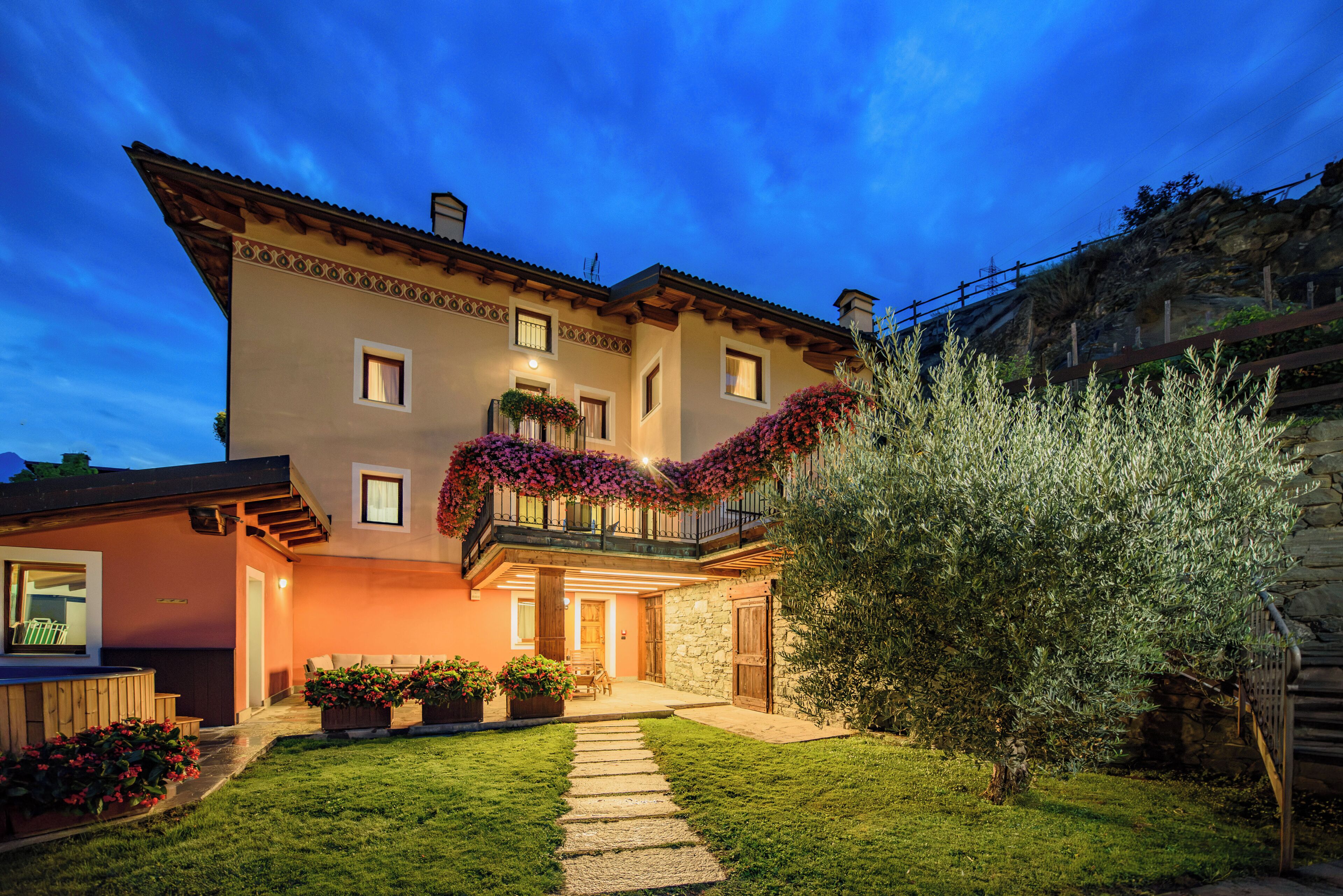 A two-story house with a balcony, a stone wall, and a well-maintained garden.