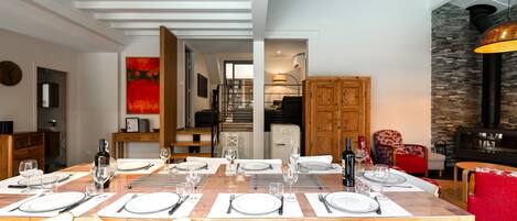 A dining area with a wooden table set for six, white chairs, and a red sofa in the background.