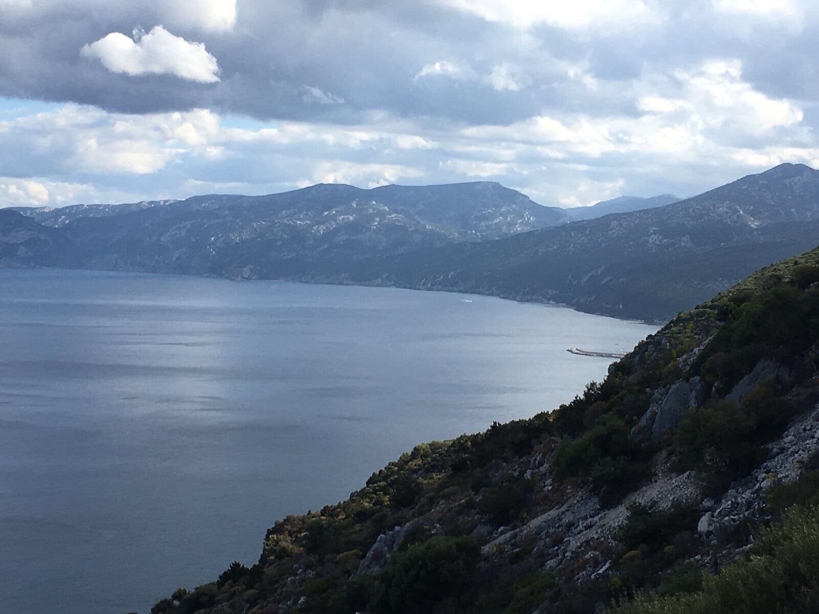 A coastal landscape with mountains in the background and a clear sky.