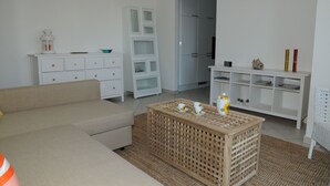 Un salon avec un canapé beige, une table basse en bois, des meubles blancs et une chaise blanche.
