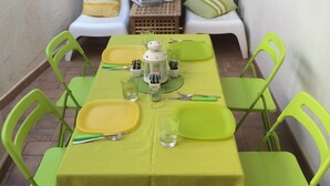 Un coin repas avec une table dressée pour quatre personnes, des chaises vertes et une porte blanche en arrière-plan.