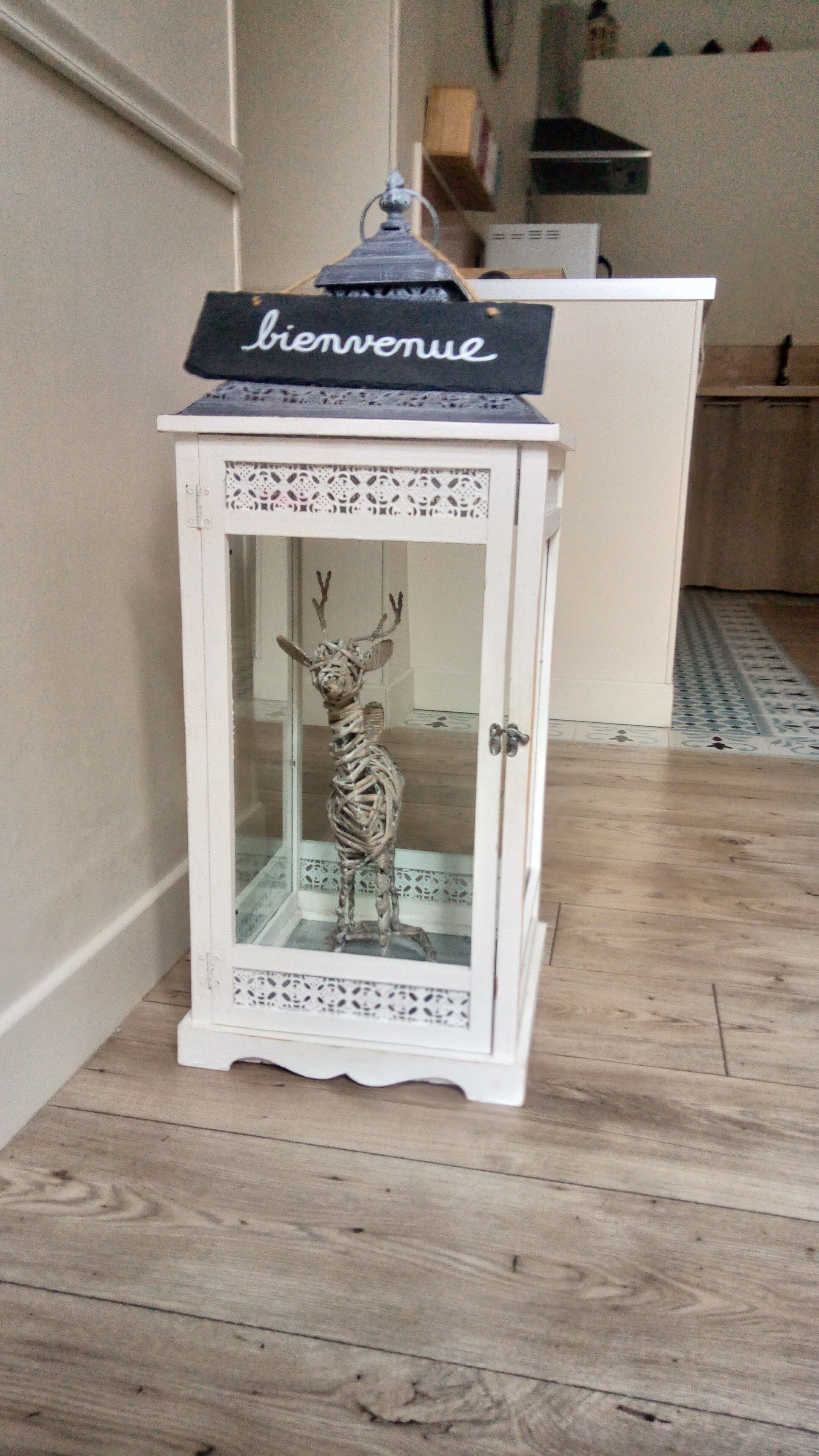 Un armari blanc amb porta de vidre i una figura decorativa de cervol.