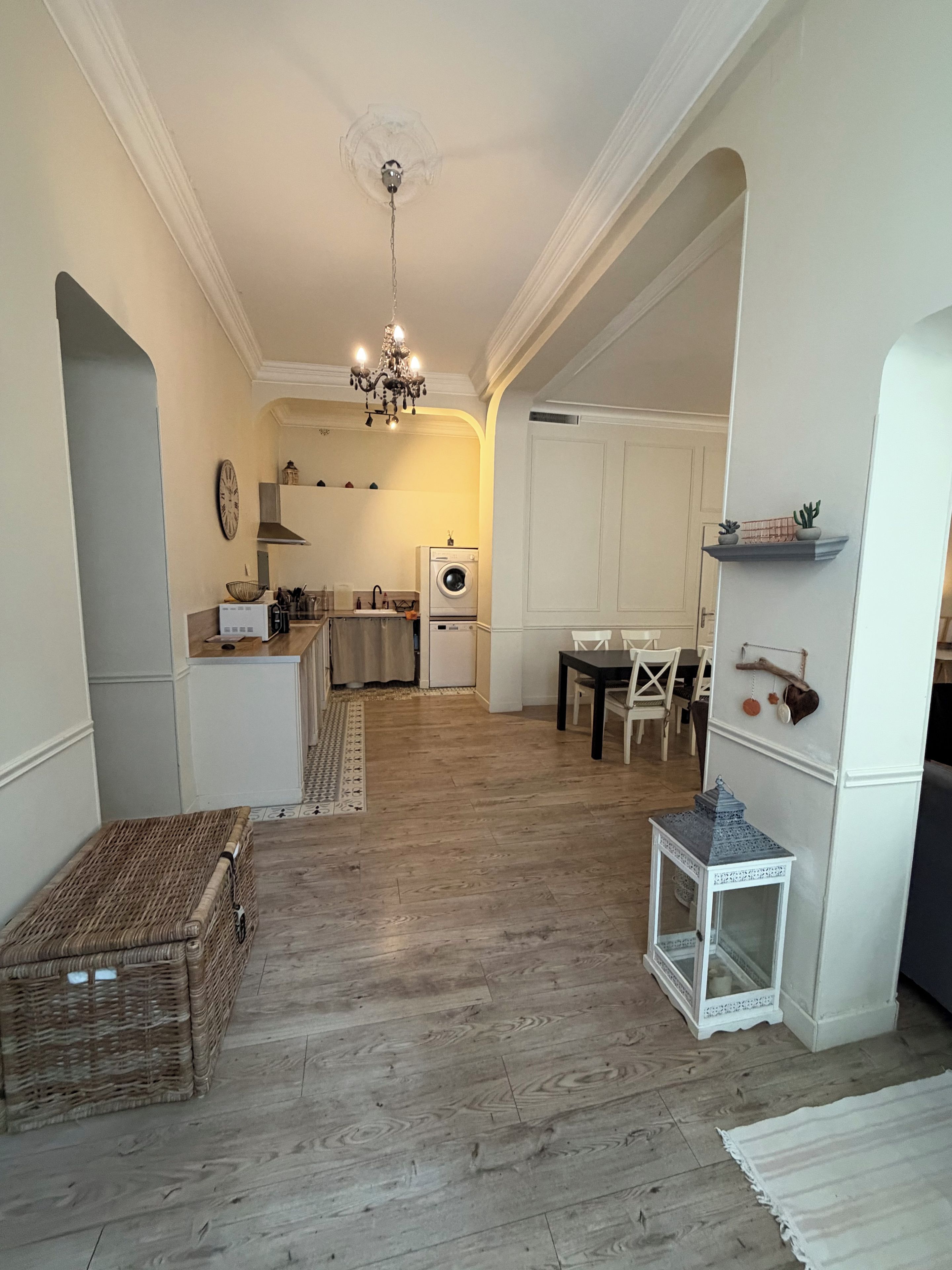 Une cuisine spacieuse avec un îlot central, un coin repas avec une table et des chaises, et un salon avec un canapé et une lampe décorative.