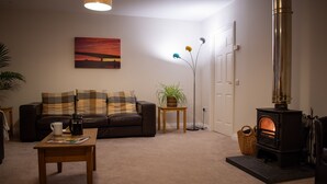Een gezellige woonkamer met een bank, salontafel en een open haard.