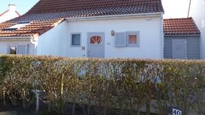 A white building with a red-tiled roof, a grey door, and a small window with shutters. - Holiday house at 800m from the beach in De Haan (De Haan)